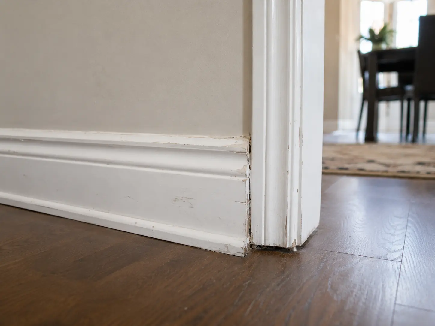 Old baseboard with gaps and worn caulking before repair